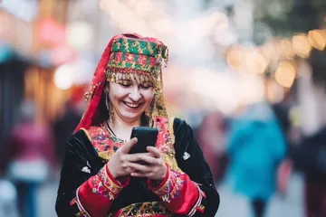 A cheerful woman in traditional clothing using her smartphone during a festive moment, showing how easily the 456DB app fits into everyday life.